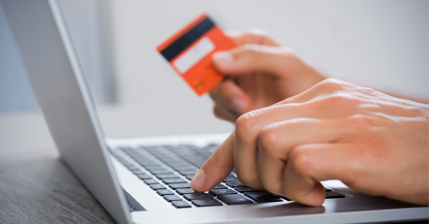 Online-Shoppen im Erotikbereich, Hand hält Kreditkarte über Laptop-Tastatur, diskreter Einkauf