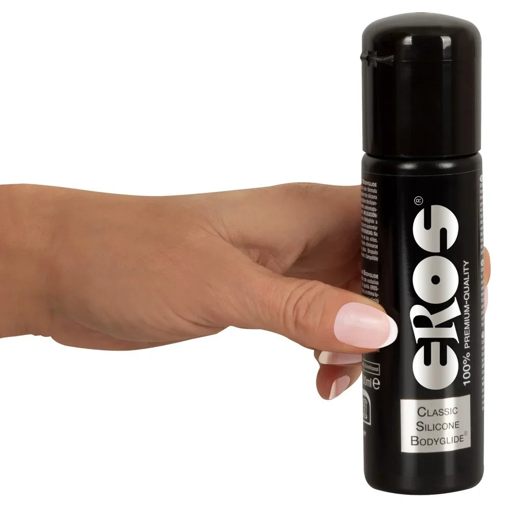 Eros Classic Silicone Bodyglide Gleitgel in schwarzer Flasche, gehalten von Hand mit rosafarbenem Nagellack
