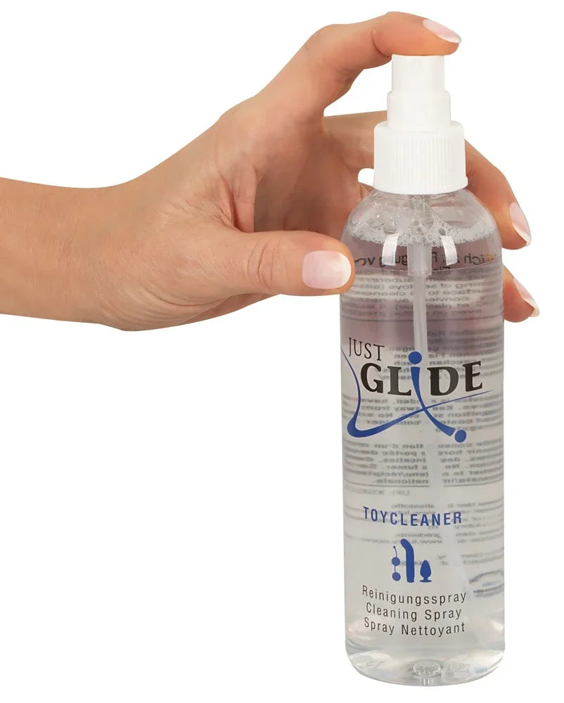 Hand hält Just Glide Toycleaner Spray, Reinigungsmittel für Intimzubehör, transparente Flasche