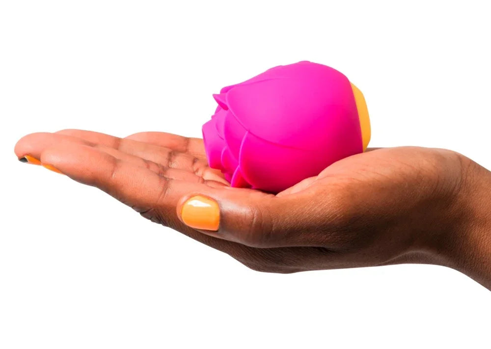 Pinkes Blüten-Vibrator in Hand mit orangefarbenem Nagellack – intim für das Liebesleben