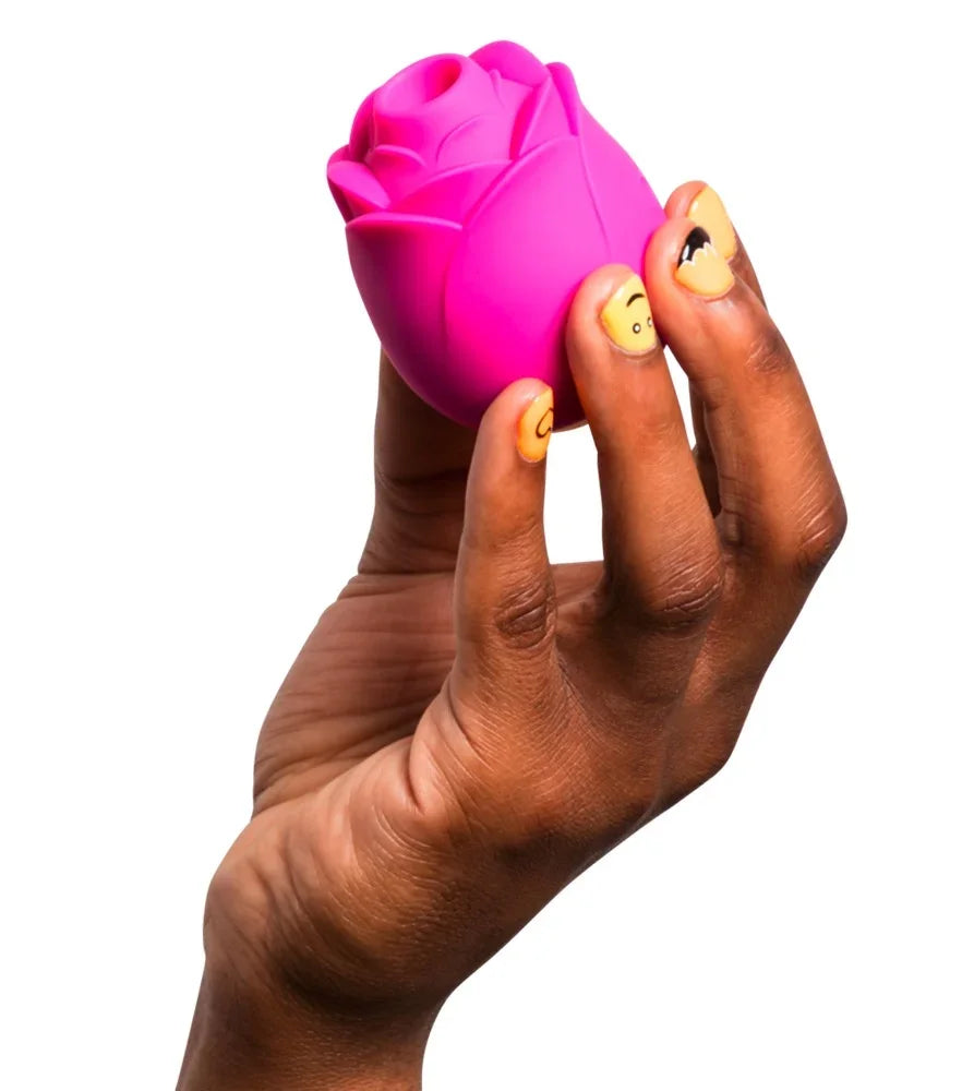 Rosa Rosen-Vibrator für das Liebesleben, gehalten in Hand mit gelbem Nageldesign