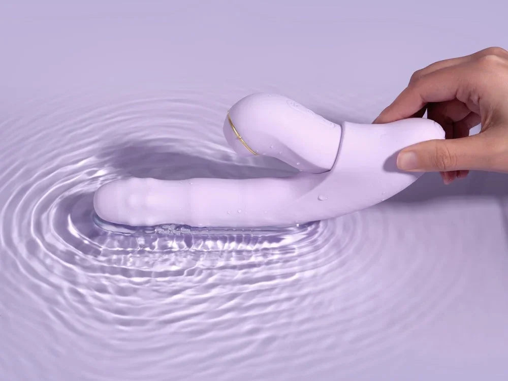 Lila wasserdichter Vibrator mit Klitorisschwinge, gehalten über Wasser
