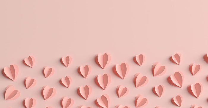 Zartrosa Papierherzen auf pastellfarbenem Hintergrund, Symbol für Liebe, Erotik und Intimität