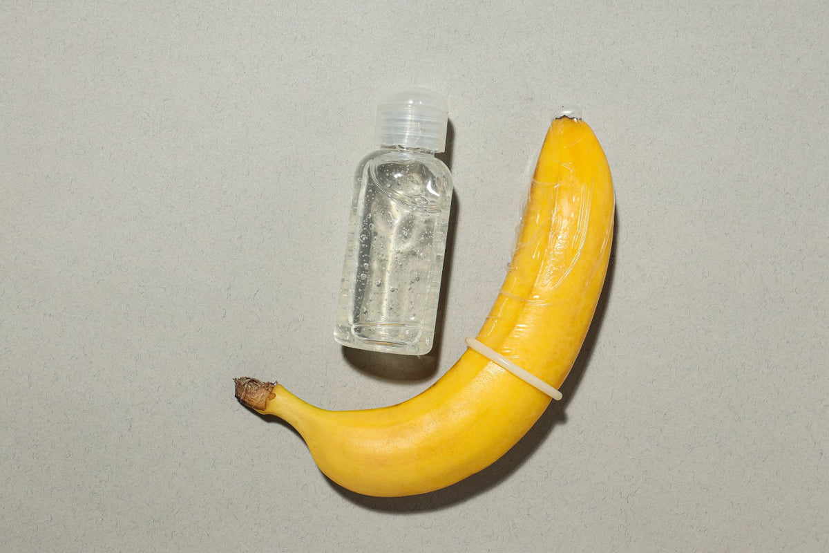 Bananen-Attrappe mit Kondom neben Gleitgel-Flasche, Sexualaufklärung, Diskretion, Onlinesexshop