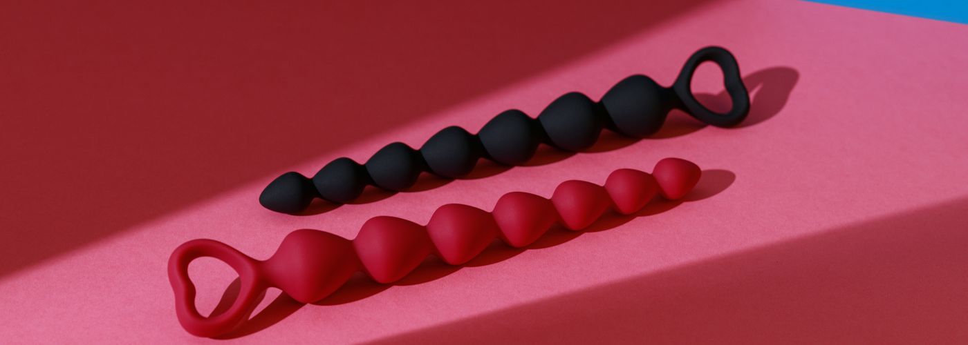 Zwei Silikon-Lustperlen in Schwarz und Rot für Paare, Deko auf rosa Hintergrund