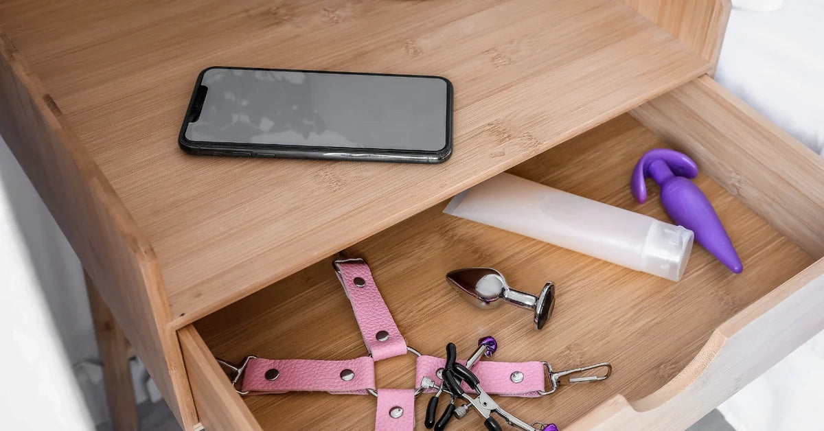 Nachttischschublade mit Vibrator, Analplug, Gleitmittel, Handschellen und Brustklammern