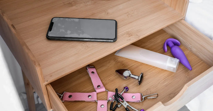 Nachttischschublade mit Vibrator, Analplug, Gleitmittel, Handschellen und Brustklammern