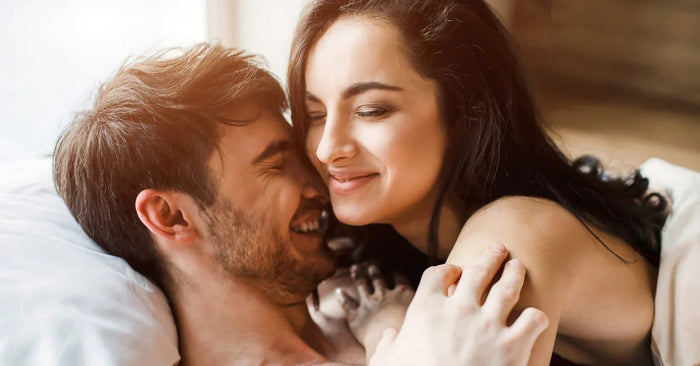 Glückliches Paar kuschelt im Bett, Erotik, Intimität und Nähe stehen im Fokus