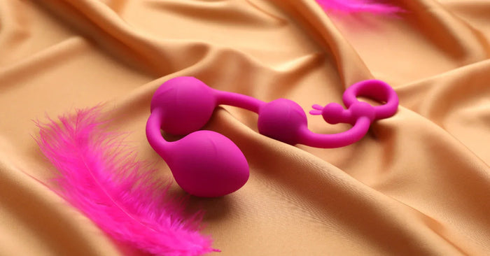 Pinkes Liebesspielzeug aus Silikon und Feder auf Satin, Sexspielzeug für Paare