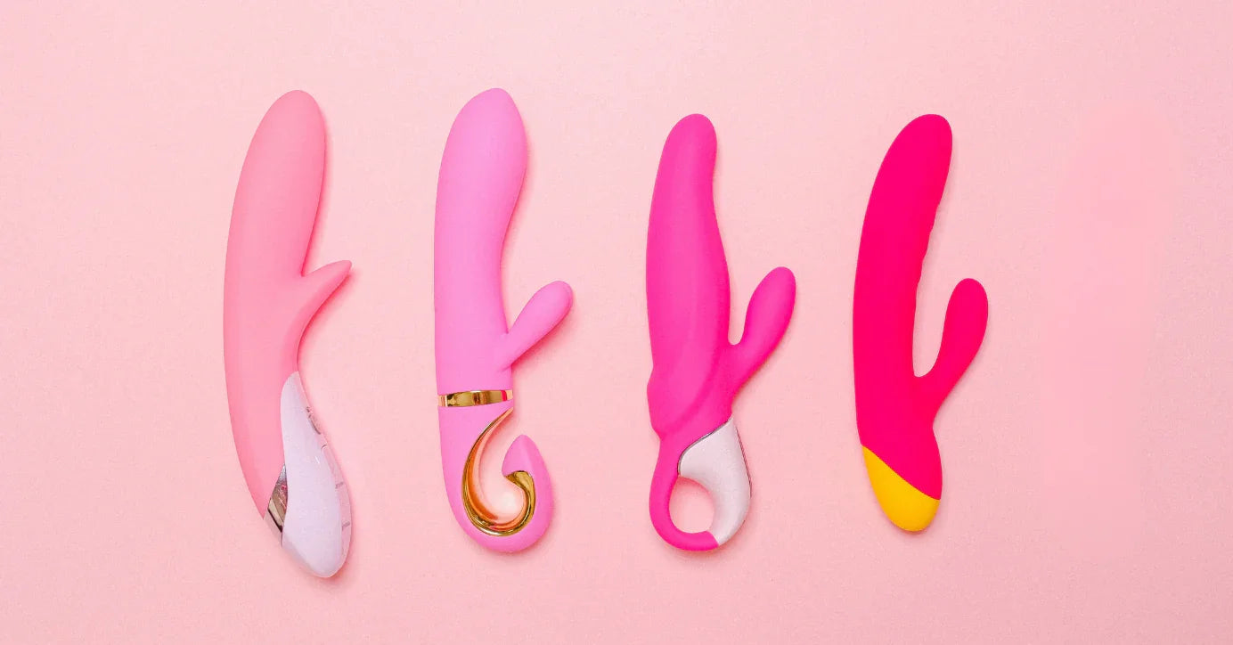 Vier pinke Vibratoren in unterschiedlichen Designs auf rosa Hintergrund, Sexspielzeug Sortiment