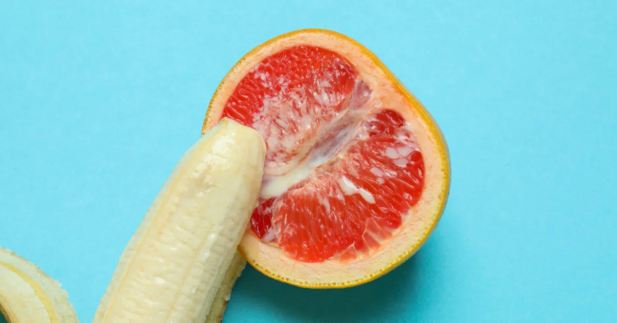 Banane und halbe Grapefruit auf blauem Hintergrund, Symbolik für Erotik und Sexualität