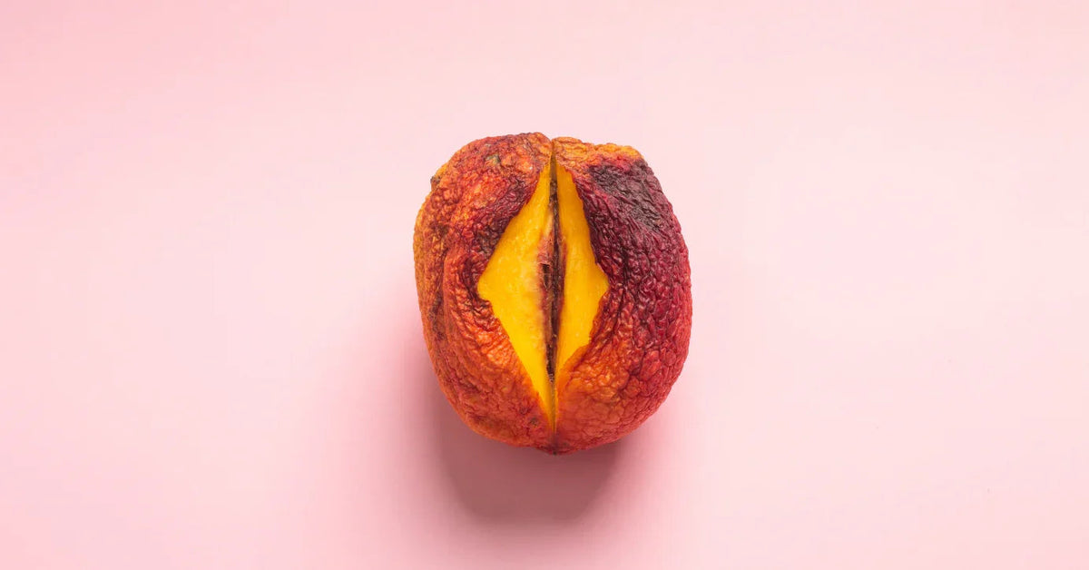 Halbierte, reife Pfirsich auf rosa Hintergrund, Symbolbild für Sexualität und Intimität