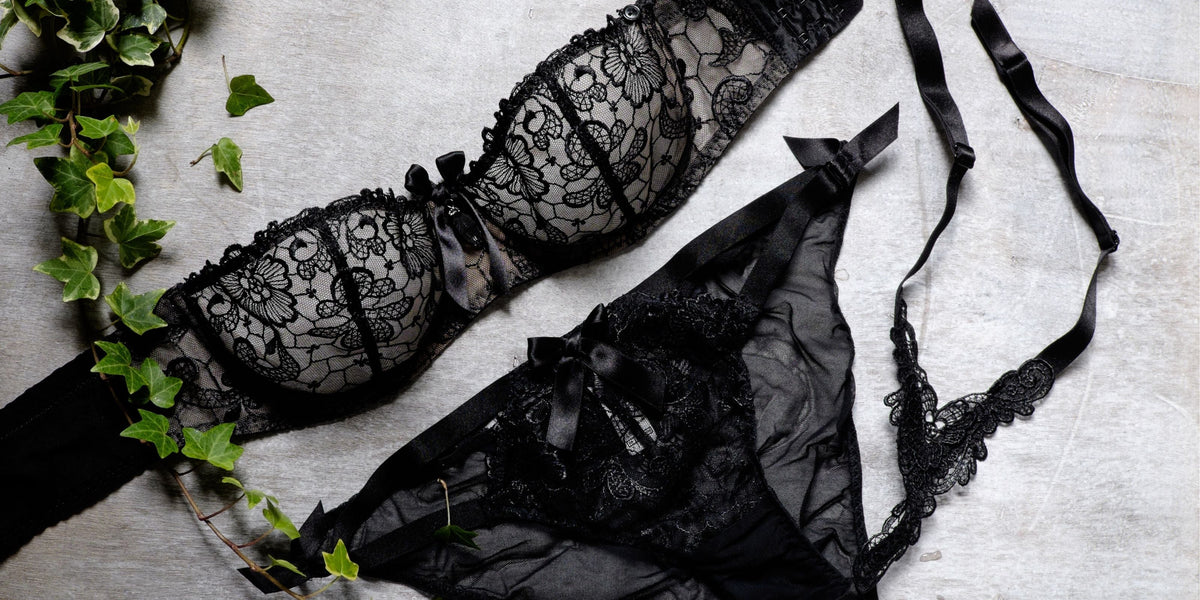 Schwarzes Spitzen-Dessous-Set mit BH und Slip, erotisch und sinnlich auf Holz mit Efeu