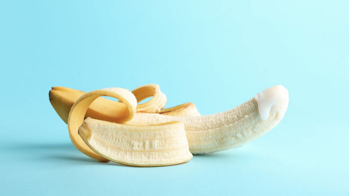 Geschälte Banane mit weißem Gleitgel, Symbolbild für Erotikprodukte vor blauem Hintergrund