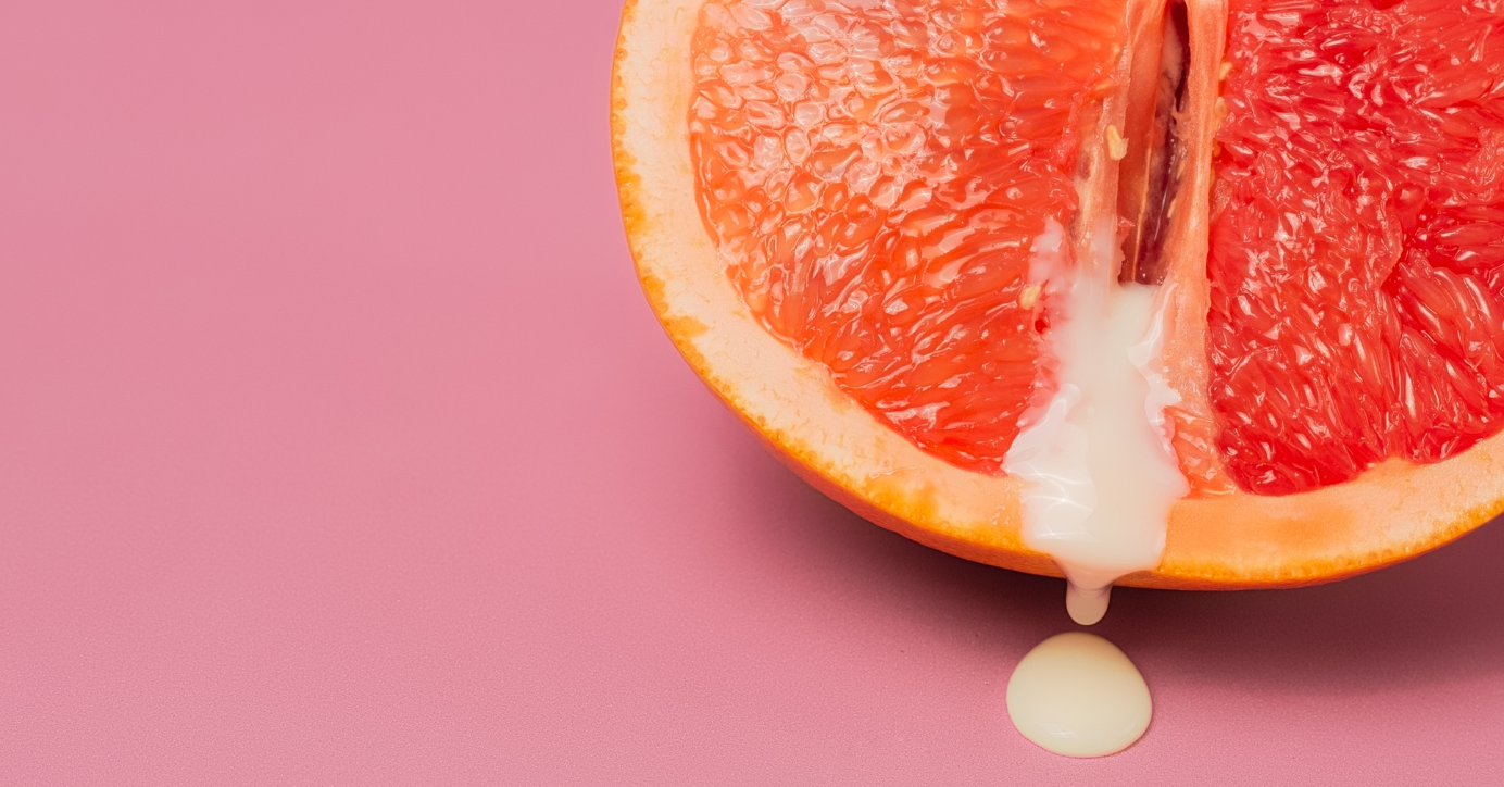 Halbe Grapefruit mit weißer Flüssigkeit auf rosa Hintergrund, Symbolbild Erotik, Gleitgel