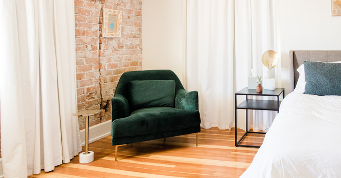 Modernes Schlafzimmer mit grünem Sessel, Nachttisch, Lampe und Doppelbett, gemütliche Atmosphäre