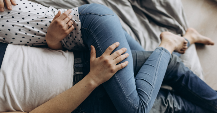 Paar liegt eng umschlungen auf Bett, zeigt Intimität und Nähe, ideales Liebesleben
