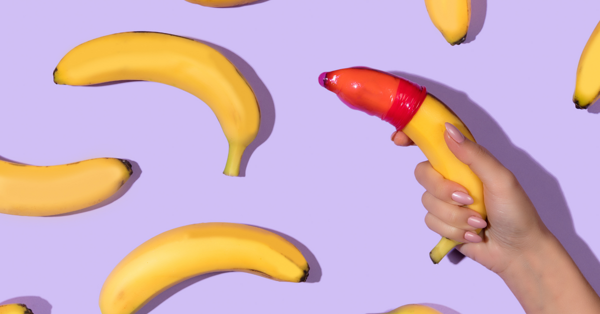 Banane mit Kondom, Hand hält Banane, Sexualaufklärung, lila Hintergrund, Aufklärung Bild