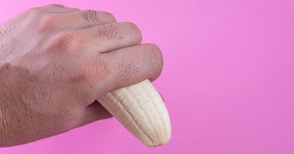 Hand hält Banane auf rosa Hintergrund, symbolisch für Erotikprodukte und Aufklärung