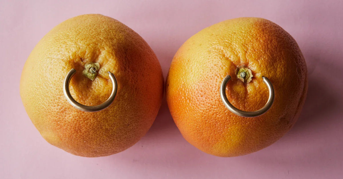 Zwei Grapefruits mit Piercings auf rosa Hintergrund, erotische Symbolik, Erotikshop