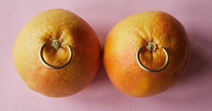 Zwei Grapefruits mit Piercings auf rosa Hintergrund, erotische Symbolik, Erotikshop
