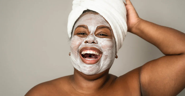 Lachende Frau mit Gesichtsmaske und Handtuchturban, Wellness und Selbstpflege