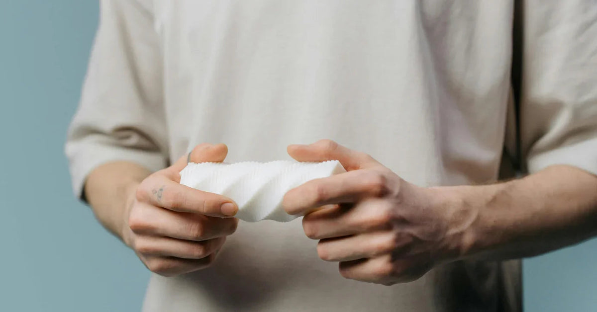 Person hält weißes Masturbator-Toy, Sexspielzeug mit Struktur, vor neutralem Hintergrund