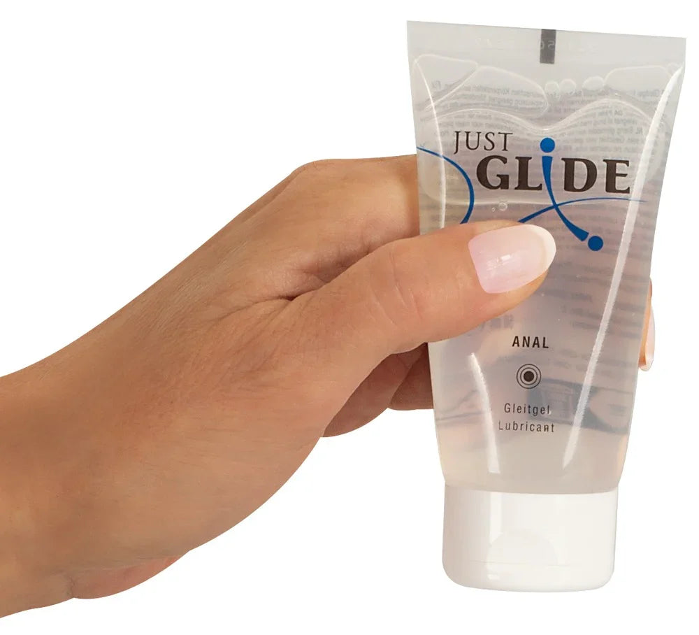 Hand hält Tube Just Glide Anal Gleitgel, transparentes Intimgel für sicheren Intimverkehr